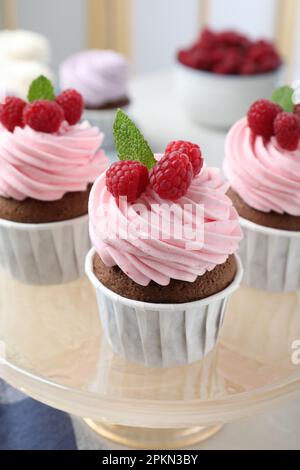 Delicious cupcakes with cream and raspberries on stand Stock Photo