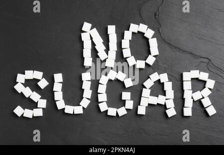Phrase No Sugar made of refined cubes on black table, flat lay Stock Photo