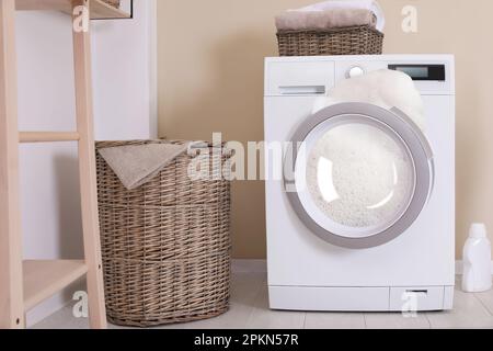 Foam coming out from broken washing machine during laundering in room Stock Photo