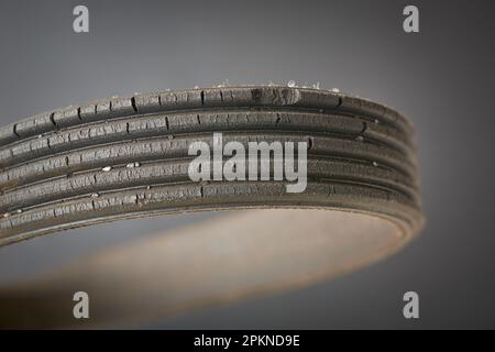 close-up of old used and worn out vehicle drive belt, isolated on gray background, failed and cracked serpentine belt with copy space, replaceable Stock Photo