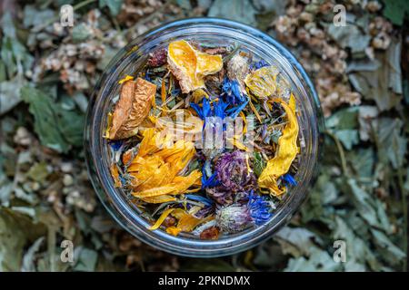 Dry flower and herbal tea leaves in a glass jar. Herbal collection of chamomile, cornflower, mint, sea buckthorn, lemongrass, wild rose, dried citrus Stock Photo