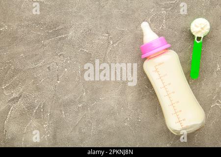 Baby milk bottle with powder on grey background. Top view Stock Photo