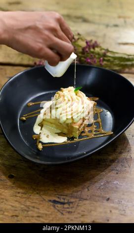 Tres leches cake or three milk cake in black plate on wooden table Stock Photo