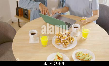 Couple eating breakfast while shopping online with credit card Stock Photo