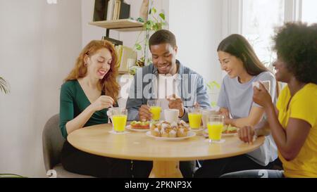 Multiethnic friends talking while having breakfast at home Stock Photo