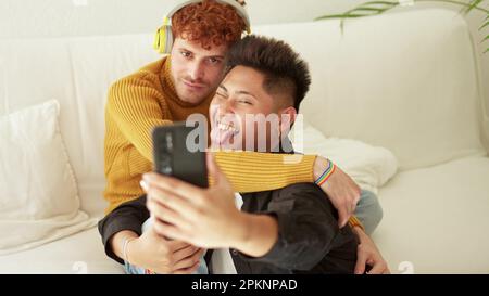 Gay couple embracing and smiling while taking selfie together Stock Photo