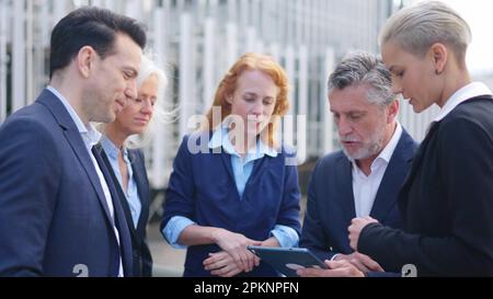 Businessman dividing tasks among his employees while using a tablet Stock Photo