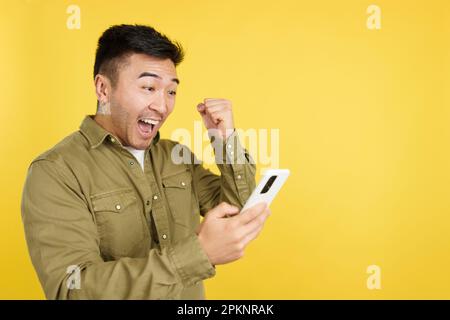 Excited chinese man celebrating while using the mobile phone Stock Photo
