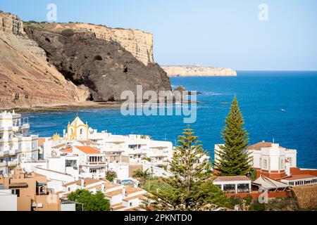 Overlooking Luz Bay from the viewpoint in May provides a tranquil rugged scene with a panoramic view of black cliff Rocha Negra and coastline. Stock Photo