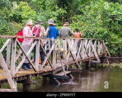 Leticia, Colombia - Dec, 2021: Trekking through rainforest of the Amazon jungle. Wooden bridge over the Tacana river. Border of Colombia nd Brazil. Am Stock Photo