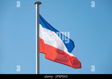 Flag of Schleswig-Holstein in Germany with stripes in blue, white and red fluttering against a clear blue sky, copy space Stock Photo