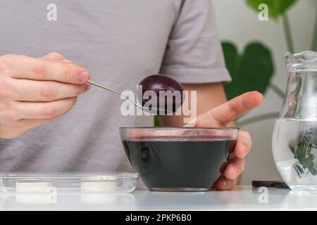 A man takes out colored Easter eggs from colored water. Dyeing easter eggs with food coloring is the first step in favorite Easter egg decorating idea Stock Photo