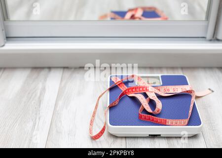 red measuring tape taken with a shallow depth of field. red measuring tape lies on the scales. diet and weight loss. High quality photo Stock Photo