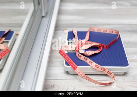 red measuring tape taken with a shallow depth of field. red measuring tape lies on the scales. diet and weight loss. Stock Photo