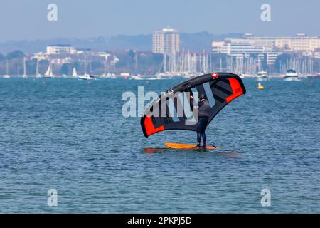 Sandbanks, Poole, Dorset UK. 9th April 2023. UK weather: warm and sunny at Sandbanks in Poole as keen watersports lovers and enthusiasts head to the sea to enjoy their activities on the water in the sunshine. Today, Easter Sunday, is forecast to be the hottest day of the year so far with the forecast of rain tomorrow. Wing boarder wing foiler in action - wingboarder wingfoiler wingsurfer wing surfer wingboarding wingsurfing wingfoiling wing boarding wing surfing wing foiling winging. Credit: Carolyn Jenkins/Alamy Live News Stock Photo