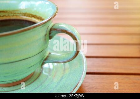 Closeup of hot coffee in a green ceramic cup isolated on wooden table Stock Photo