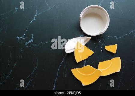 Broken white and yellow pottery scattered on black floor Stock Photo
