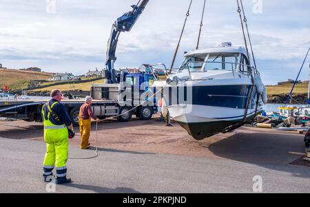 Lifting a small cabin cruiser from the water for repairs in the small harbour at Bridge End, West Burra, Shetland Isles, Scotland Stock Photo