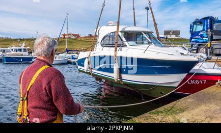 Lifting a small cabin cruiser from the water for repairs in the small harbour at Bridge End, West Burra, Shetland Isles, Scotland Stock Photo