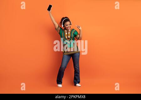 Positive cool black woman enjoying nice music app Stock Photo