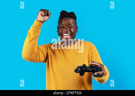 Video Gaming Concept. Euphoric African American Man With Joystick Celebrating Game Win Stock Photo