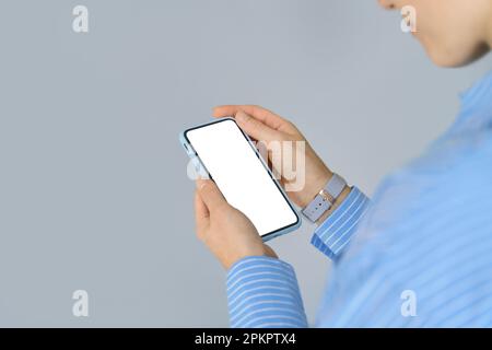 Female hands holding cell phone with mock up white mobile screen. Close up Stock Photo
