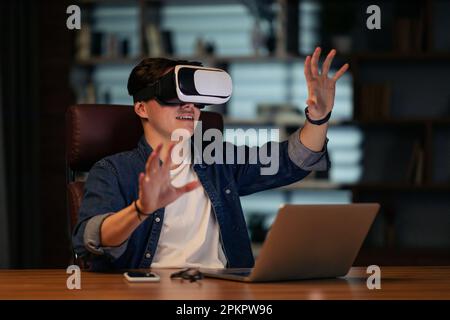 Young businessman using laptop and wireless VR headset at workplace Stock Photo