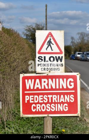 A road sign: 'Warning, Slow, Pedestrians Crossing'. Stock Photo