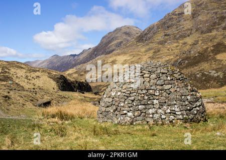 A domed Stone Cairn within the imposing mountains of Glen Coe in the Scottish Highlands Stock Photo