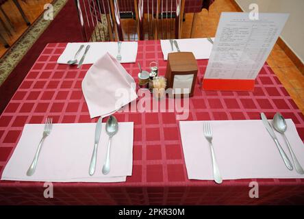 Table served for lunch in the dining room of restaurant: spoons, forks, knives. Stock Photo
