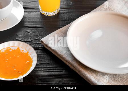 White empty plate mock up on wooden table. Coffee cup, jam, orange juice on a rustic dark background. Food mockup. Empty dish template. Continental br Stock Photo