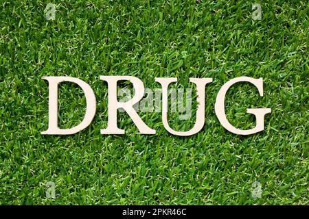 Wood alphabet letter in word drug on artificial green grass background Stock Photo