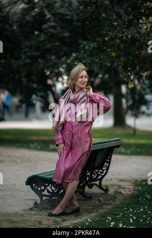 A woman in a futuristic pink raincoat in the park. Stock Photo