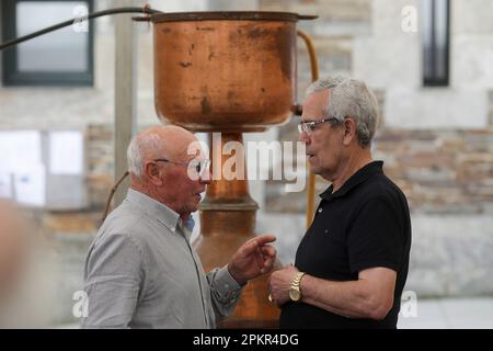 Two men converse in front of an alquitara during the 51st edition of