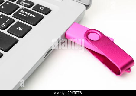 Laptop with pink USB flash drive isolated on white background Stock Photo