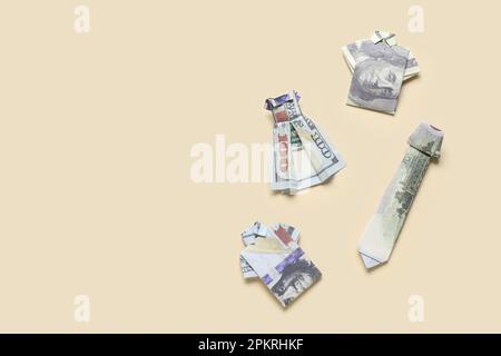 Origami clothes made of dollar banknotes on beige background Stock Photo