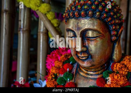 Close up of bronze buddha statue sitting in meditation with flower decorations for festival ceremony. High quality photo Stock Photo