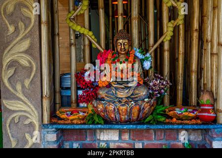 Bronze buddha statue sitting in meditation with flower decorations for festival ceremony. High quality photo Stock Photo