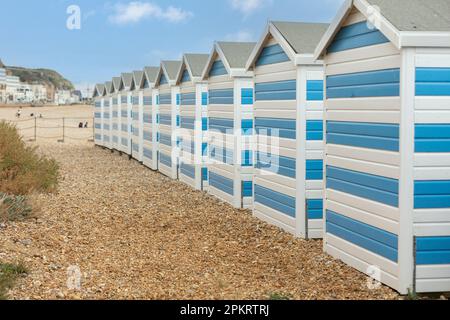 Hastings, united kingdom, 24, August 2022 Blue and white striped beach houses on a sunny beach in hastings Stock Photo