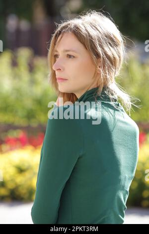 Outdoor portrait of woman on a beautiful sunny day in a green cotton turtleneck Stock Photo
