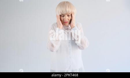 Portrait of an elderly woman suffering from a headache on a white background. Stock Photo