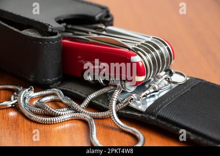 Multifunctional knife on a wooden table black leather case Stock Photo