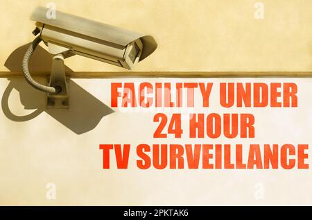 Video surveillance and security. A CCTV camera is installed on the wall of the building, next to it is written - Facility under 24 hour TV surveillanc Stock Photo