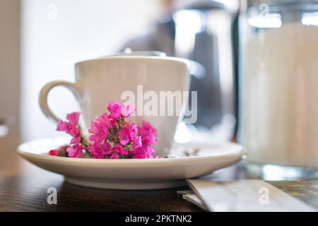 White porcelain coffee cup with pink flowers on a brown wooden table. Still life. Stock Photo