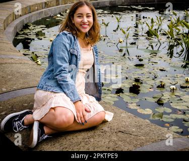 Female Asian Teen Seated Beside a Lily Pond | De Young Museum Stock Photo