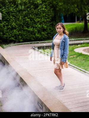 Asian Teen Walking on Misty Walkway | De Young Museum Gardens | Female | Short Dress Denim Jacket Stock Photo