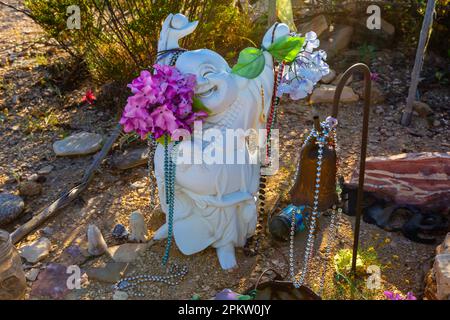 A small statue of a monk on a decorated grave in the old Terlingua Texas cemetery.  A happy monk. Stock Photo