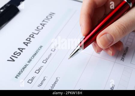 Woman filling visa application form for immigration, closeup Stock Photo