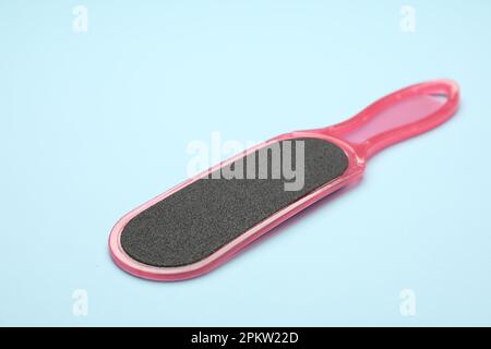 Pink foot file on light blue background, space for text. Pedicure tool Stock Photo