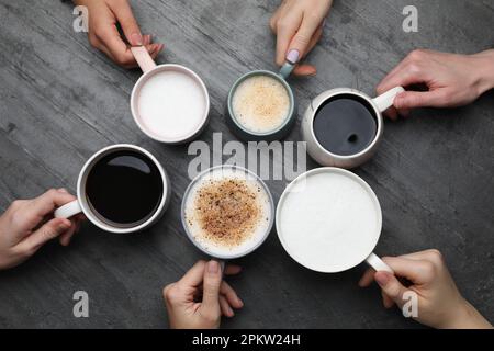 People holding different cups with aromatic hot coffee at grey table, top view Stock Photo